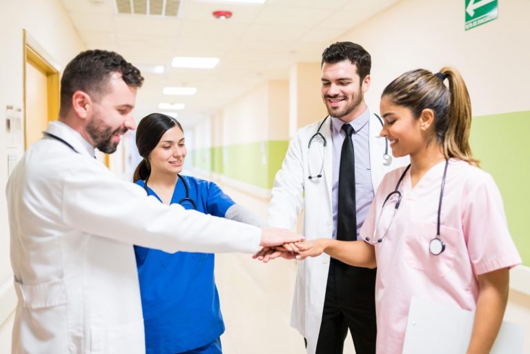 confident male female doctors stacking hands while standing corridor hospital
